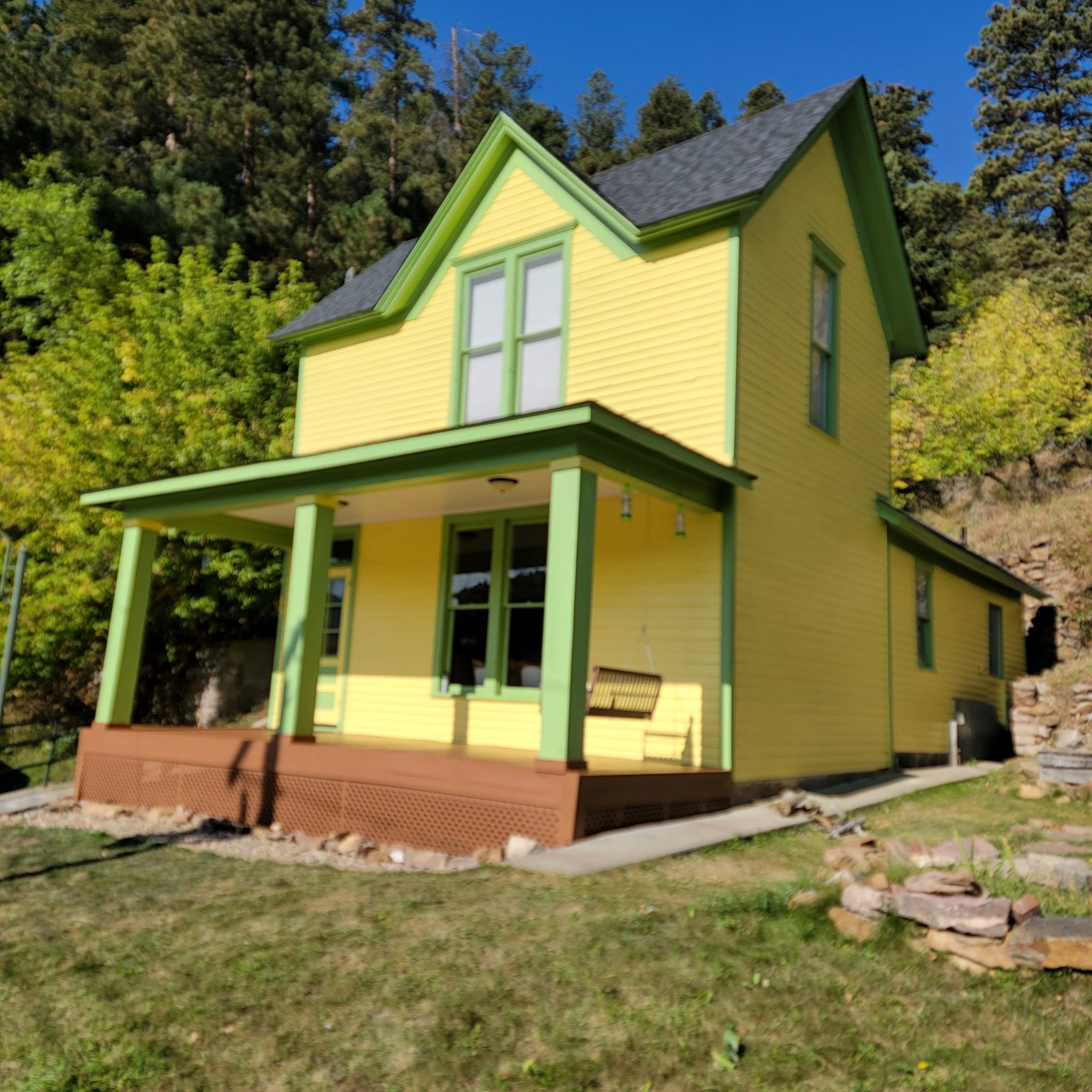 Yellow Victorian home with green trim and a freshly painted exterior