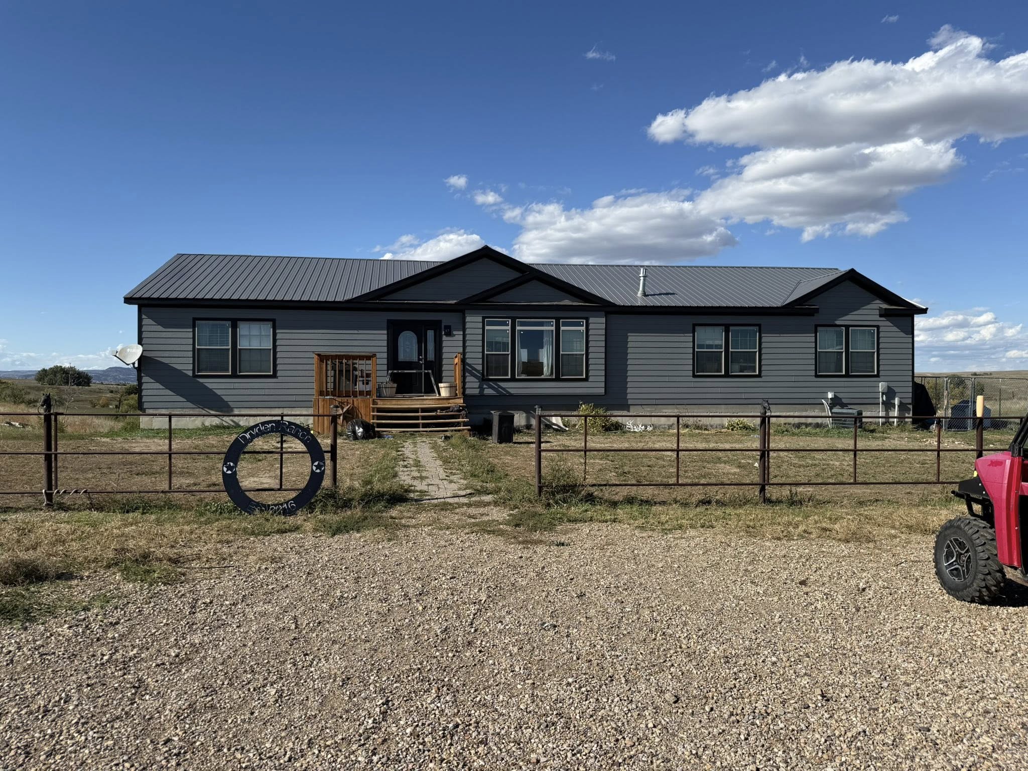 Gray ranch-style home with dark trim and a standing-seam metal roof