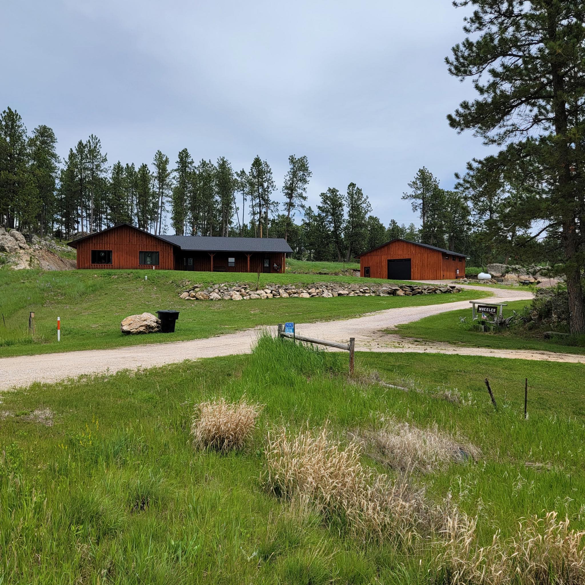 Cedar-stained ranch home and matching outbuilding among Black Hills pines